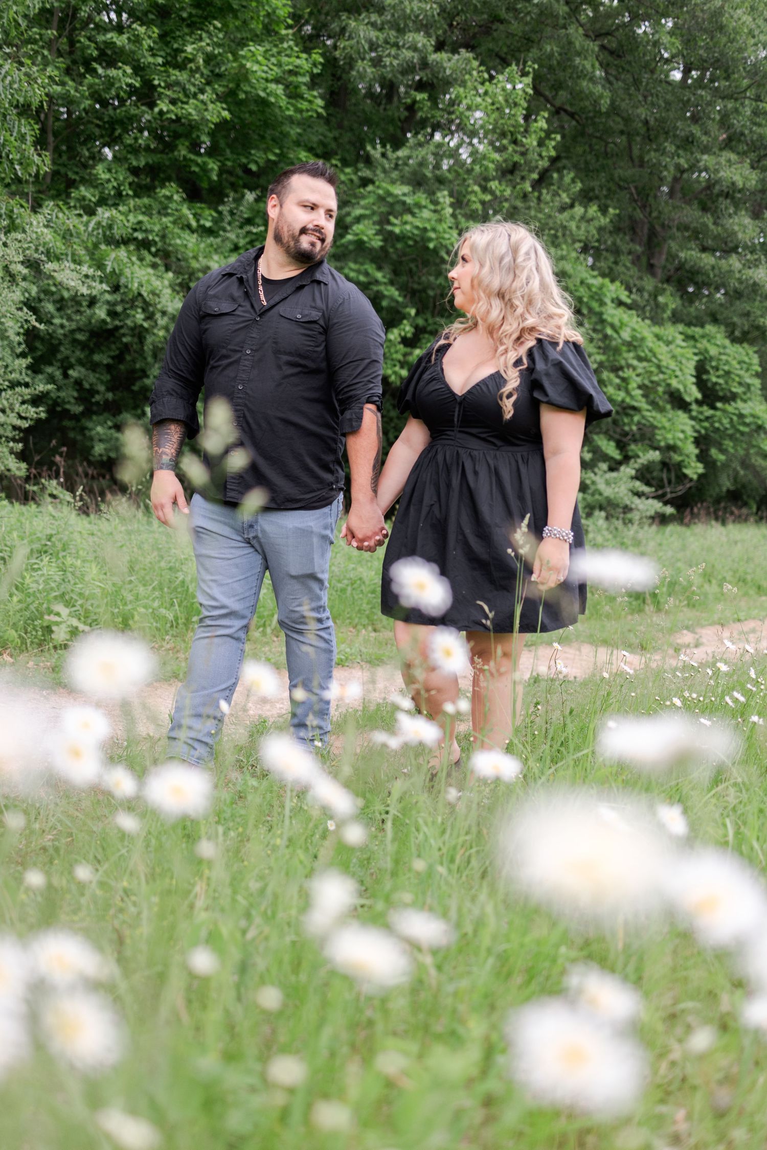 Couple walking through a meadow of daisies on a sunny spring day.
