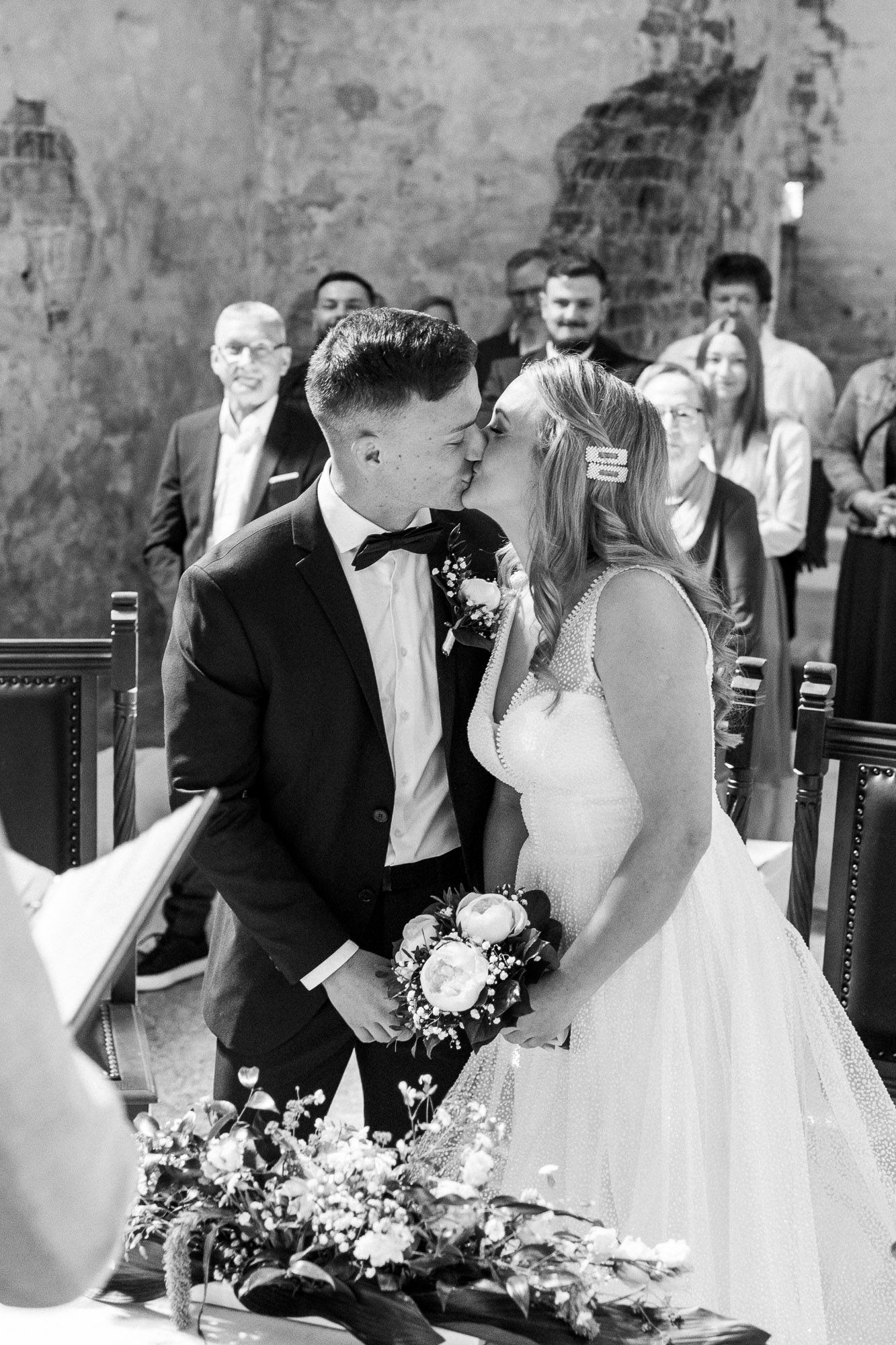 Black and white wedding ceremony scene in a rustic stone venue.