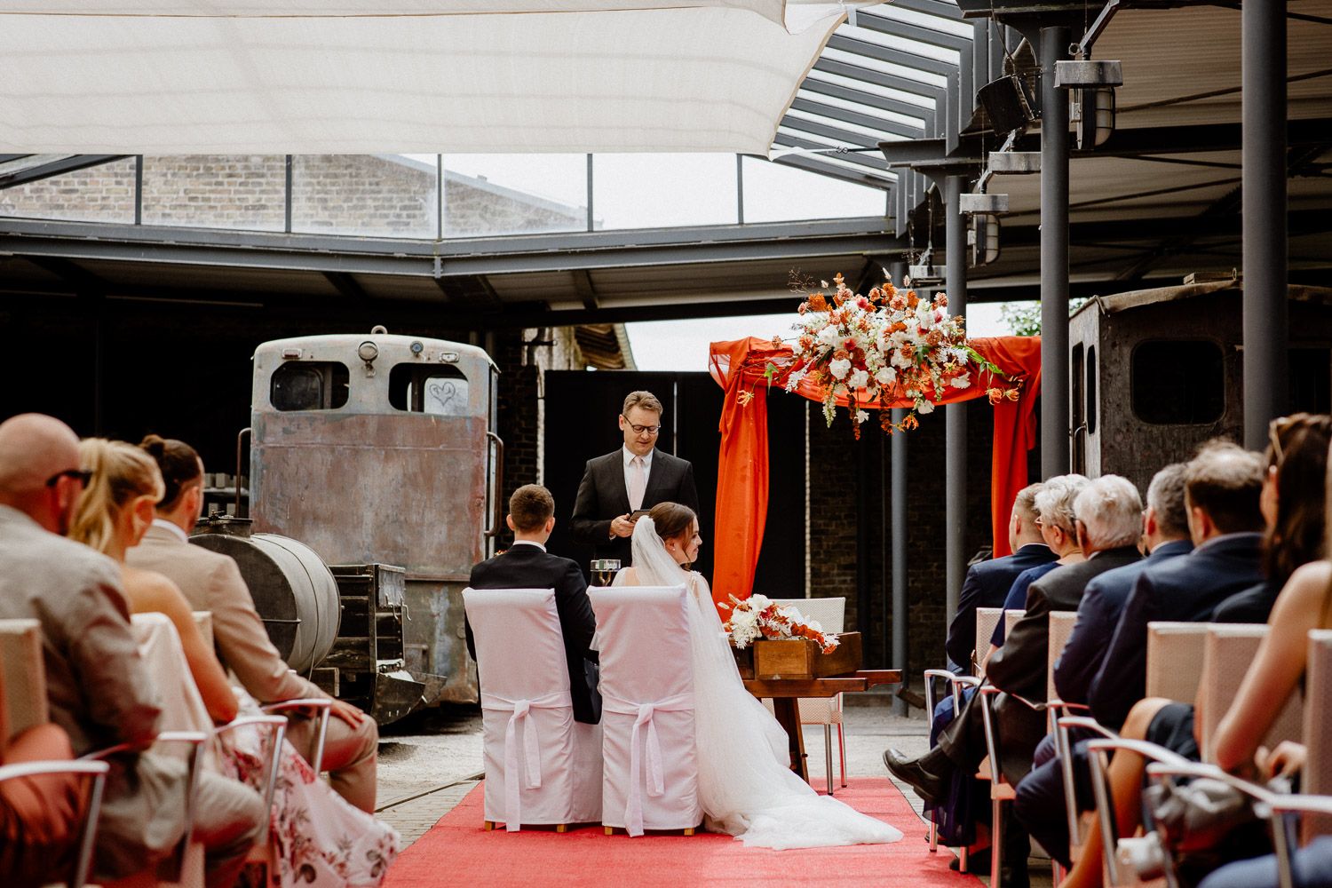Modern indoor wedding venue with glass walls and elegant ceremony setup.