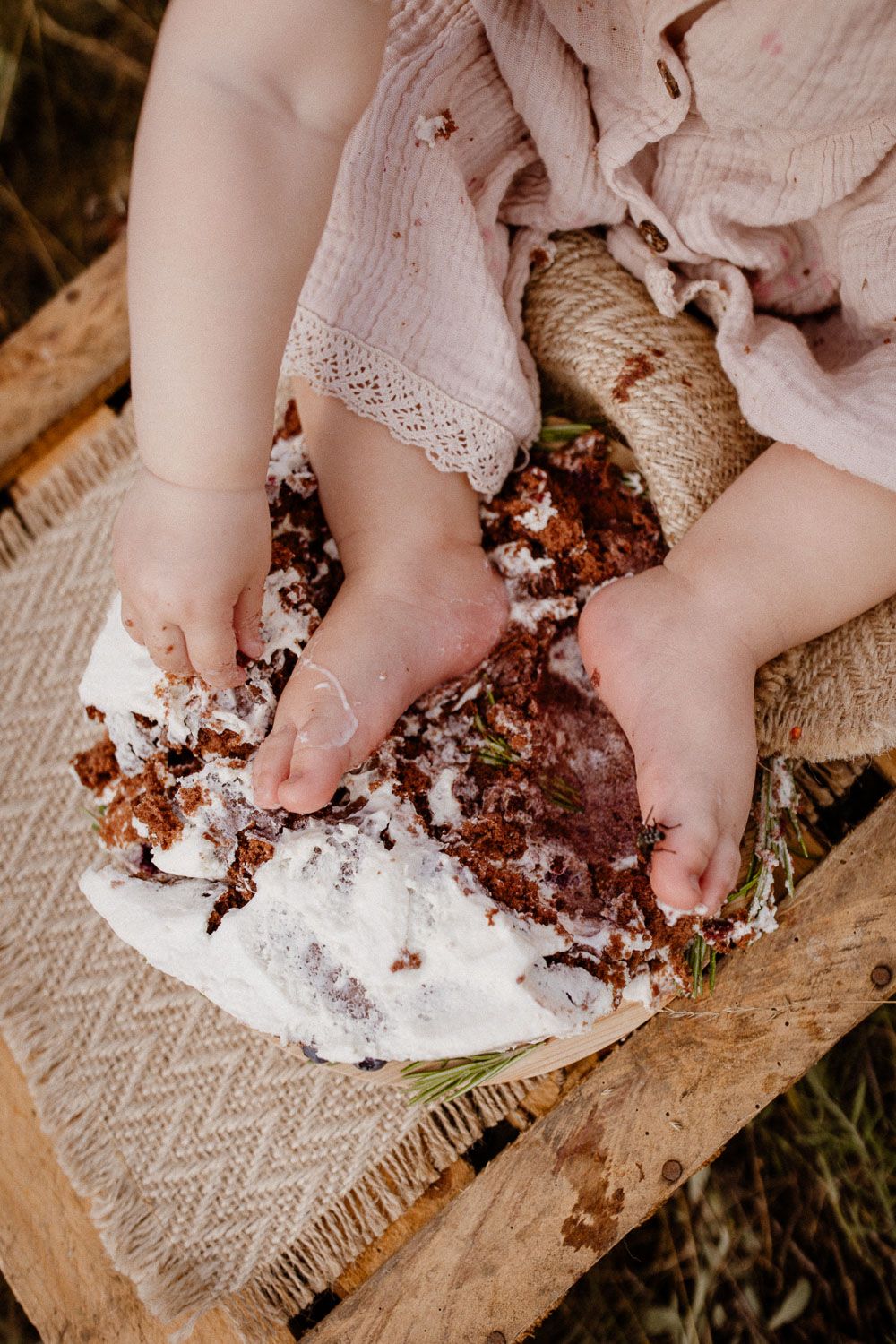 Close-up of small feet smashing into chocolate cake on wooden surface.