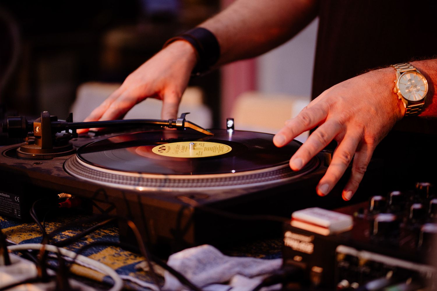 Close-up shots of hands operating DJ turntables and equipment in dark lighting.