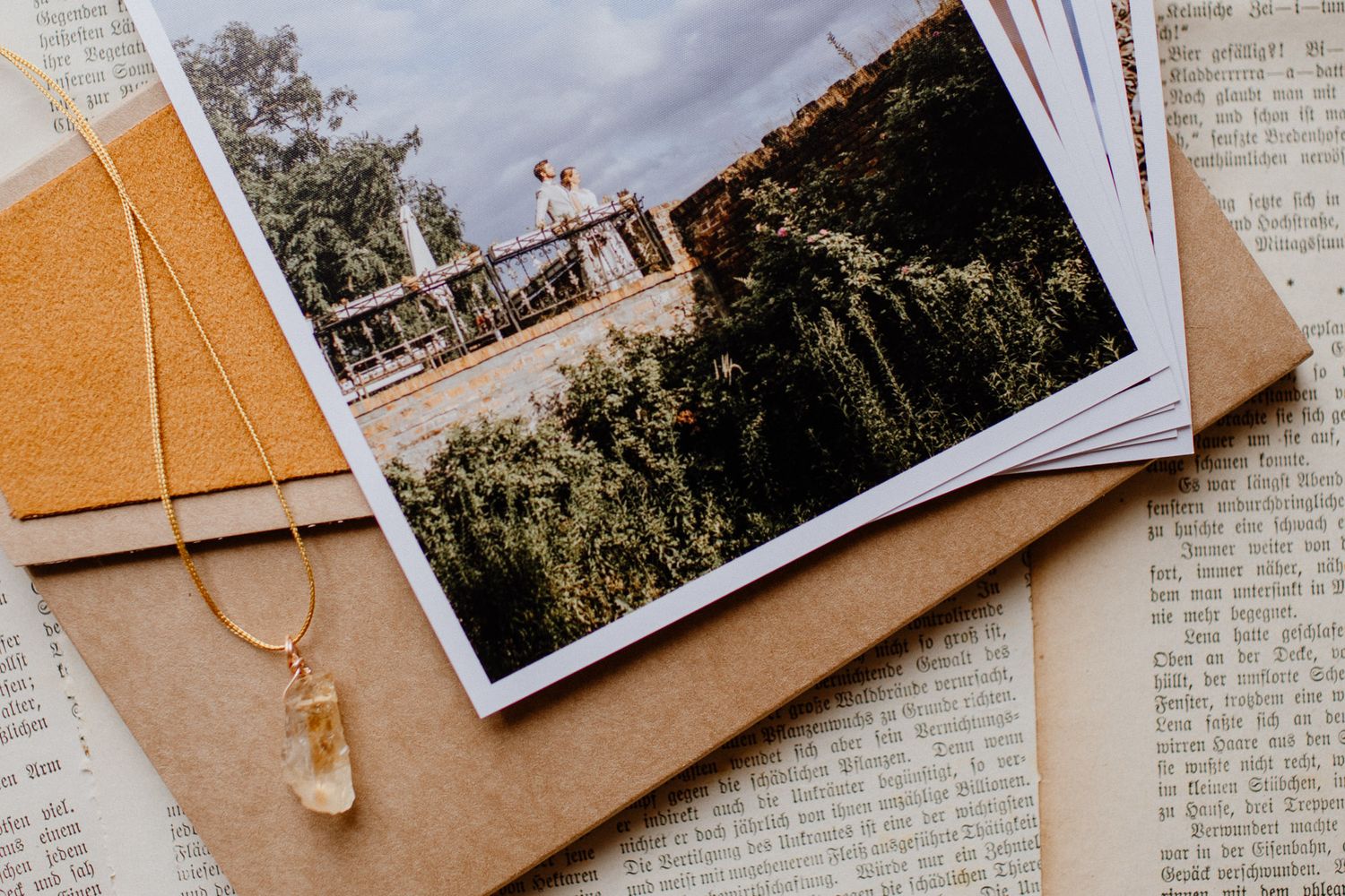Wedding photo and necklace arranged on brown paper with book pages.