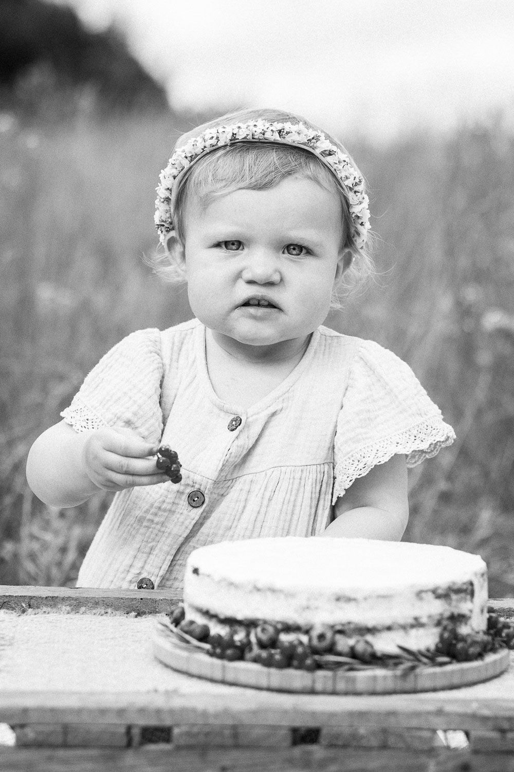 Black and white portrait with cake on rustic wooden table in outdoor setting.