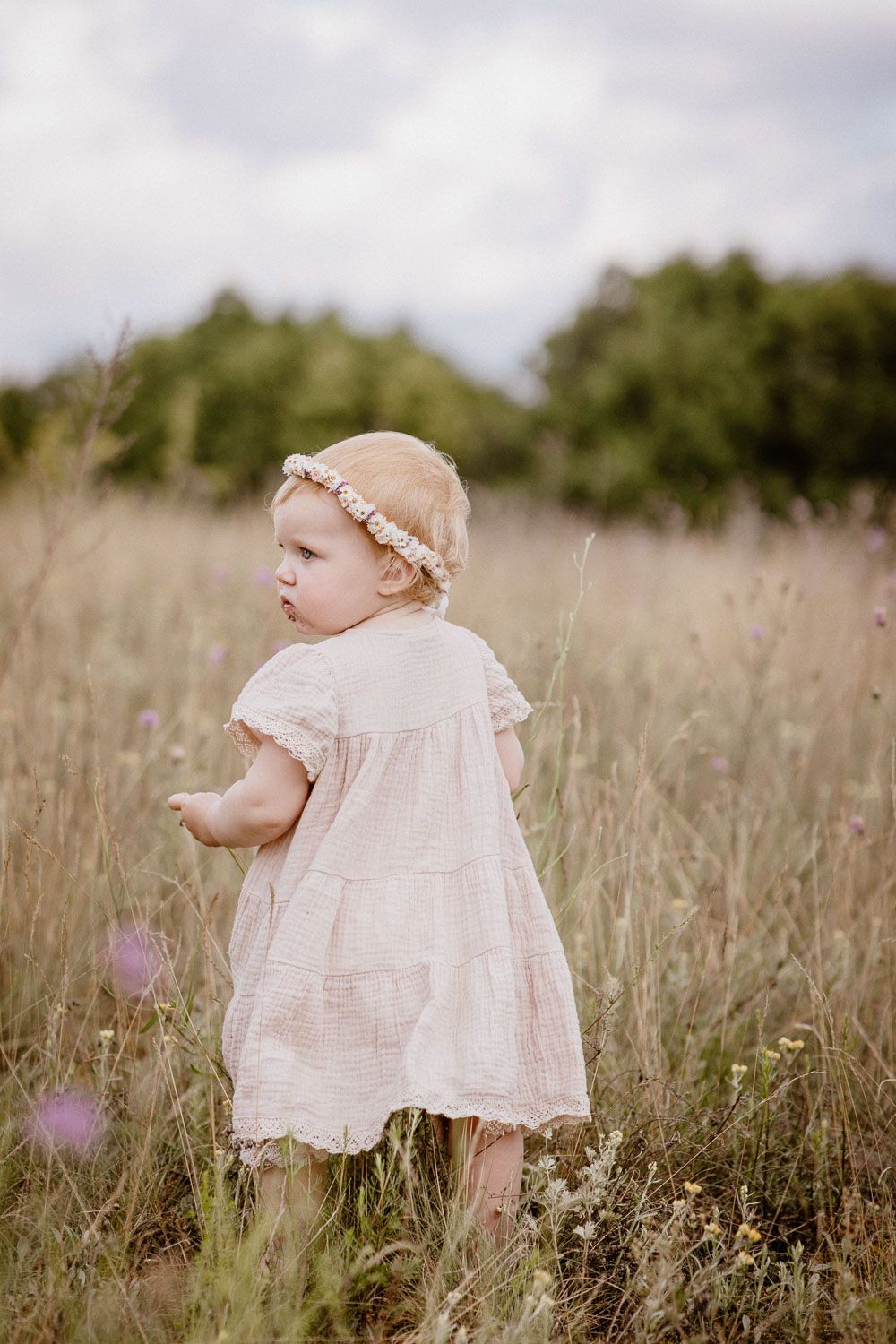 Soft light captures lace dress detail in tall grass field.