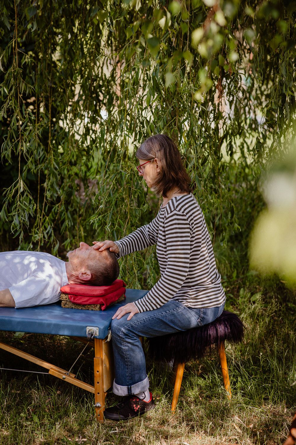 A relaxation therapy session takes place outdoors under a willow tree.