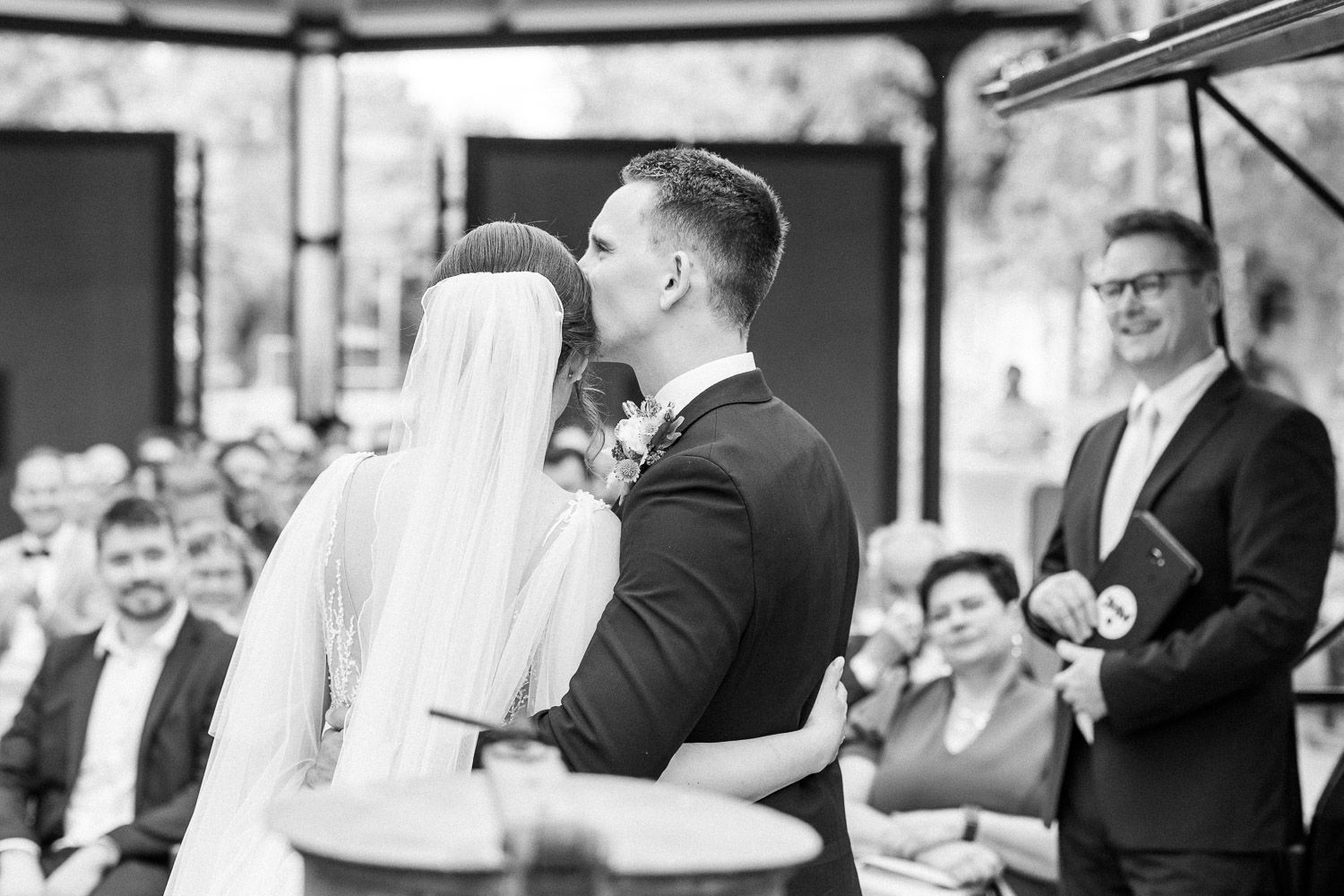 A tender moment captured during a wedding ceremony with guests looking on.