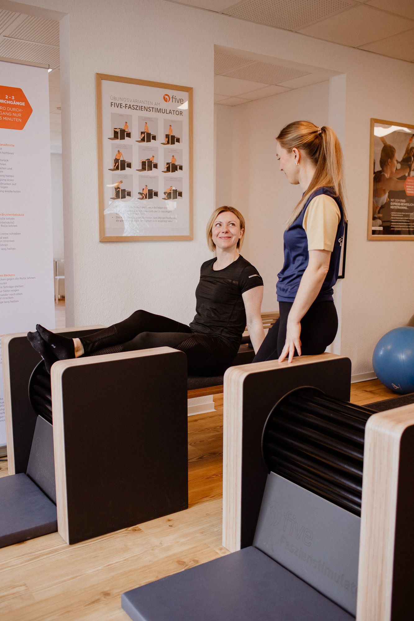 People demonstrating fitness exercises on black padded equipment in a modern gym studio.