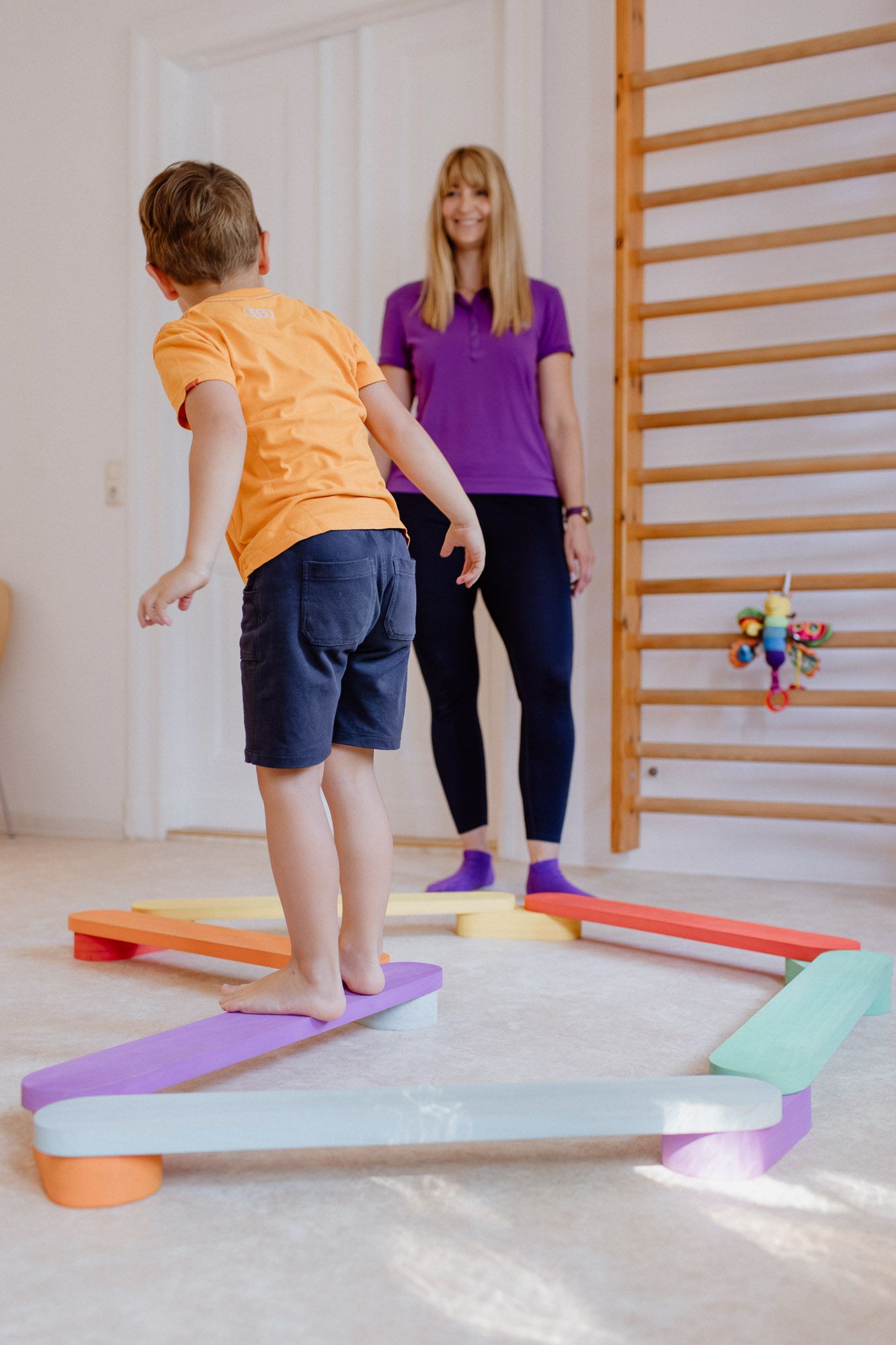 Child practicing motor skills with colorful balance beams and exercise equipment.