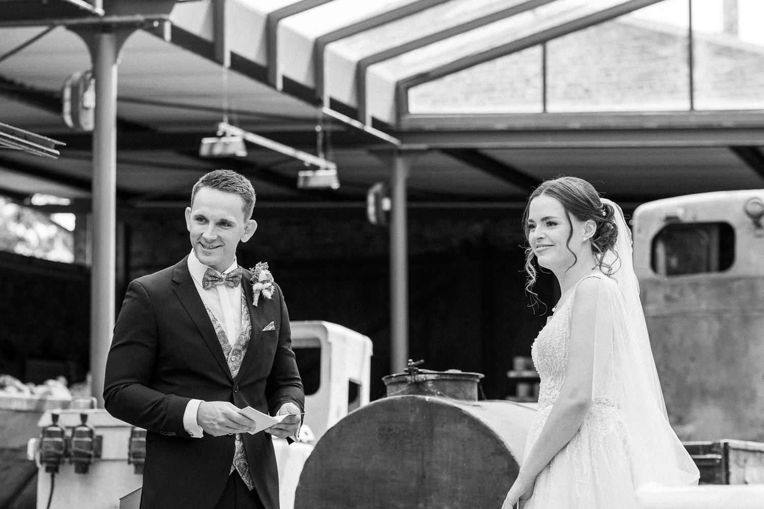 A couple exchanges vows during an outdoor wedding ceremony under a covered venue.