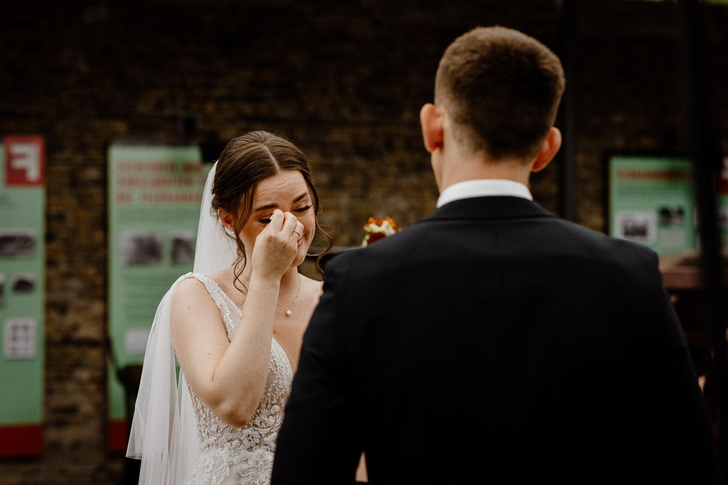 Intimate wedding ceremony moment captured in a dimly lit rustic indoor setting.