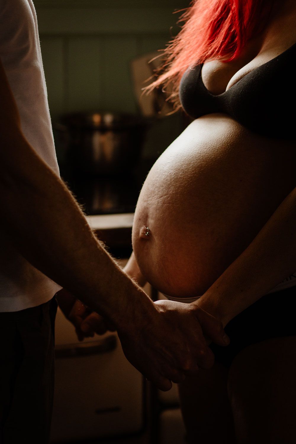 Close-up shots of pregnant belly being gently touched and cradled in dim lighting, showing tender moments of maternity.