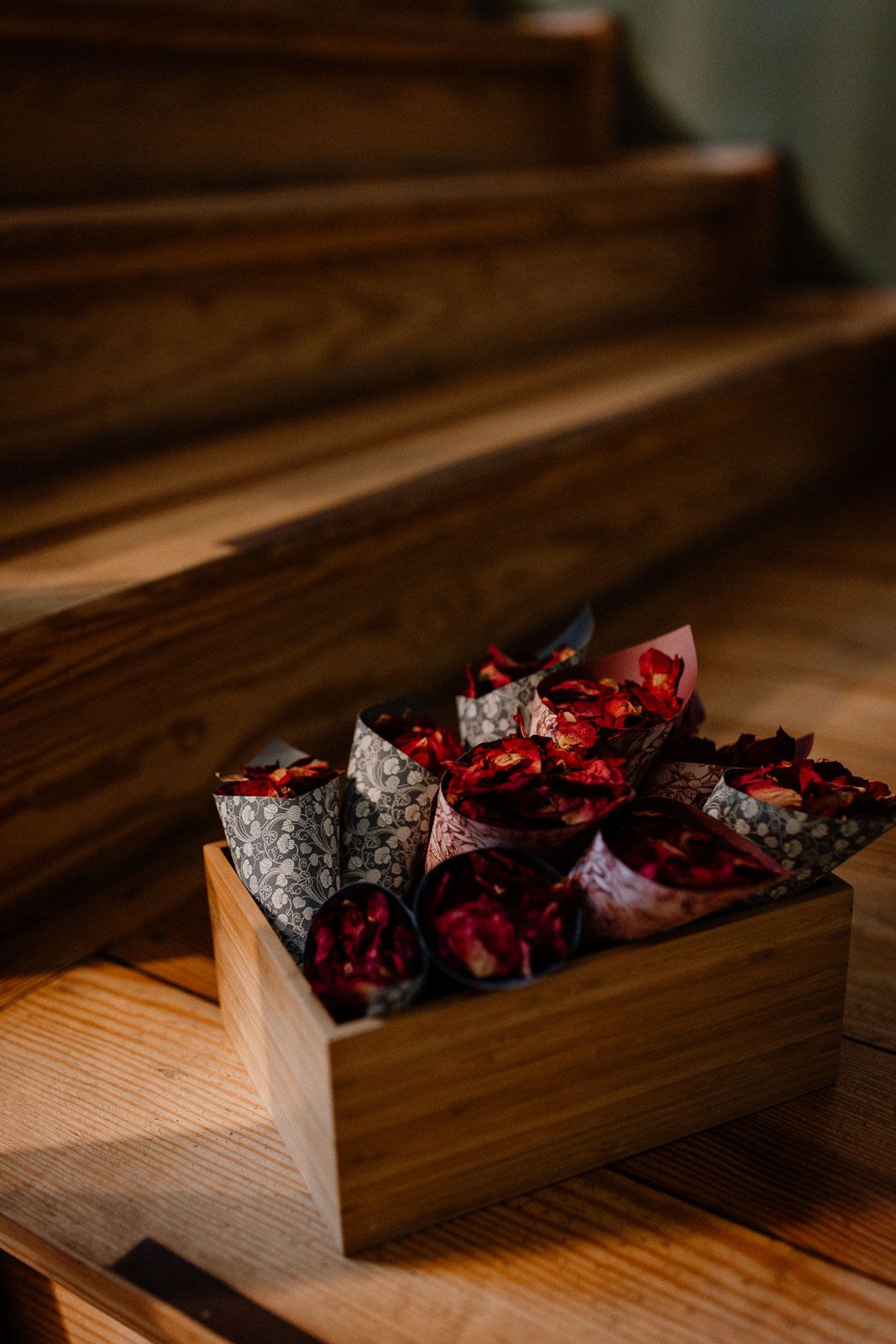 Dried red and black potpourri petals arranged in a rustic wooden tray create an elegant decorative display.