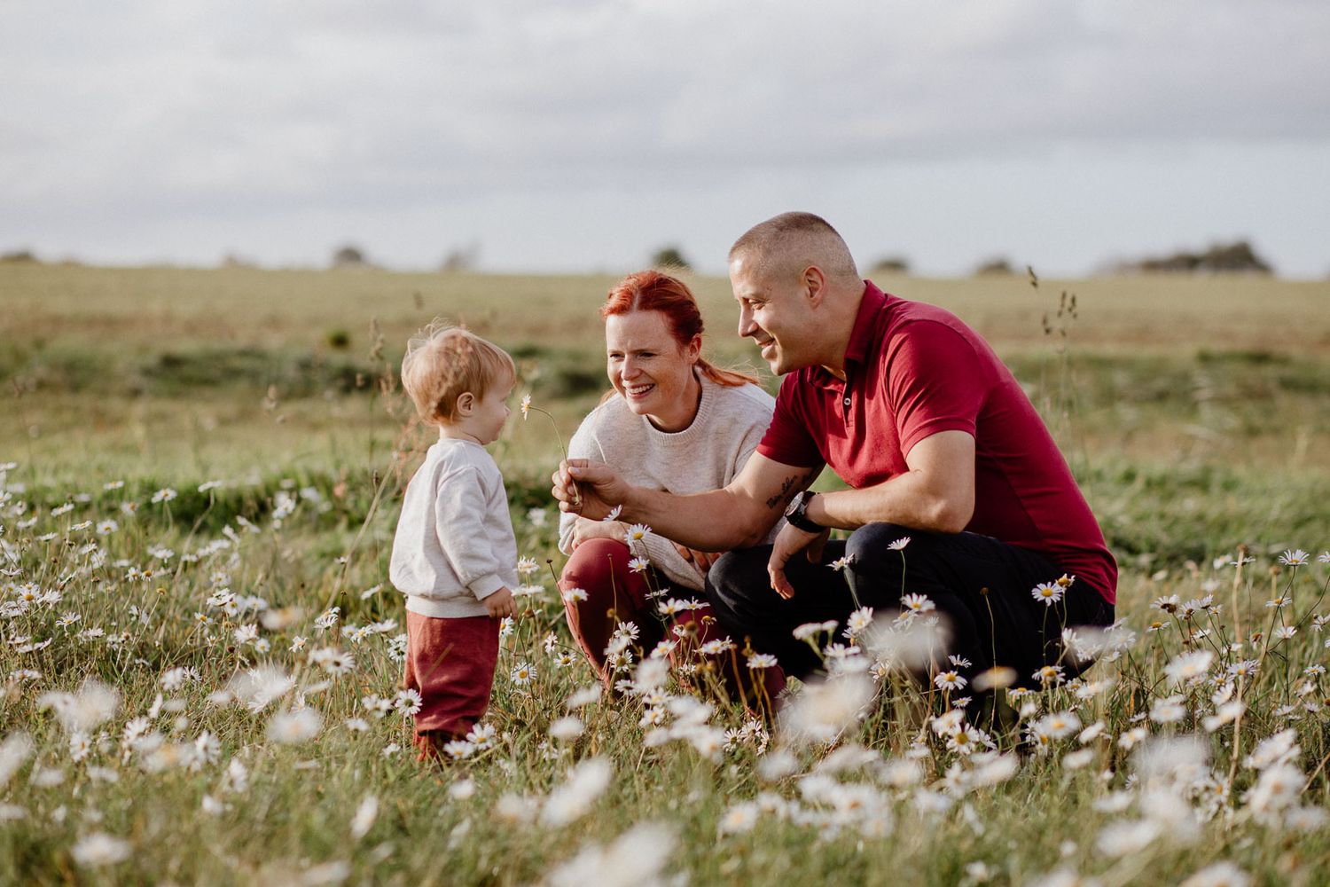 Family enjoying time together in a wildflower meadow on a sunny day.