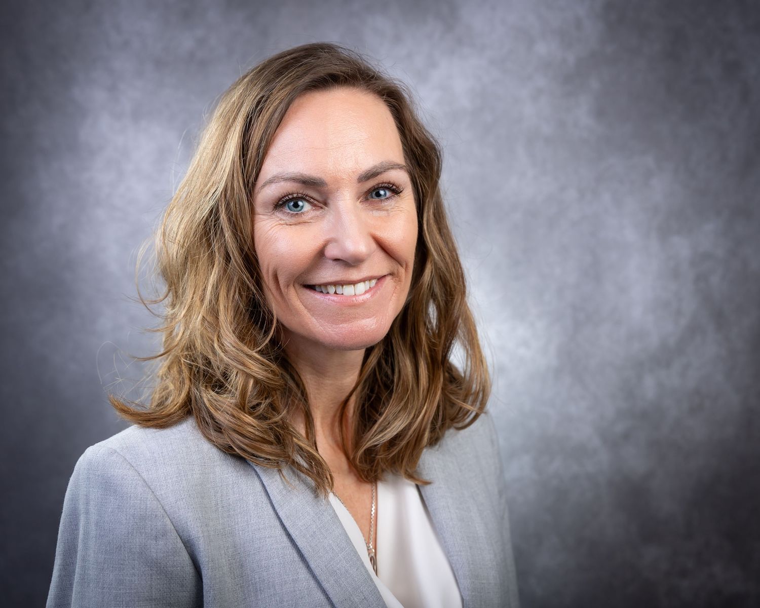 Professional headshot series showing different expressions against a gray studio backdrop.