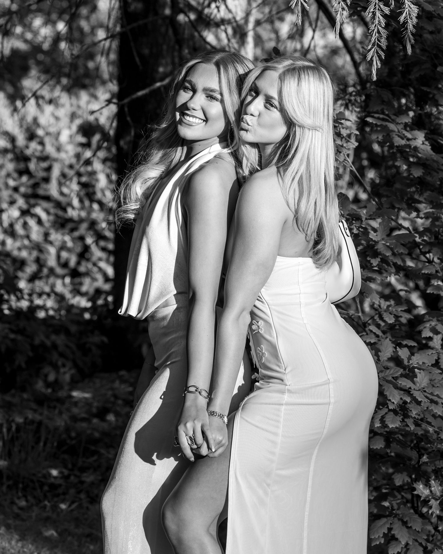 Black and white portrait of two white dresses in garden setting.