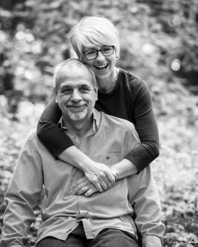 Black and white portrait of couple embracing outdoors with natural background.
