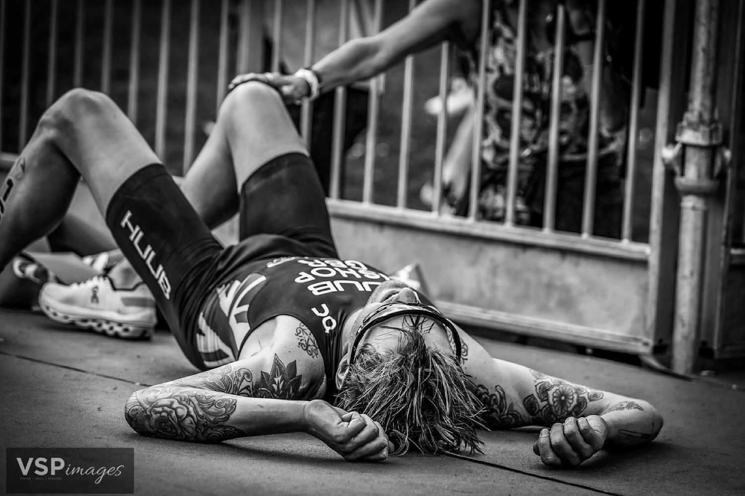 A person in workout gear lies exhausted on the ground after an intense training session in black and white photography.