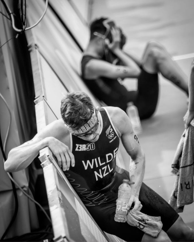 An exhausted athlete rests and hydrates between competition events.