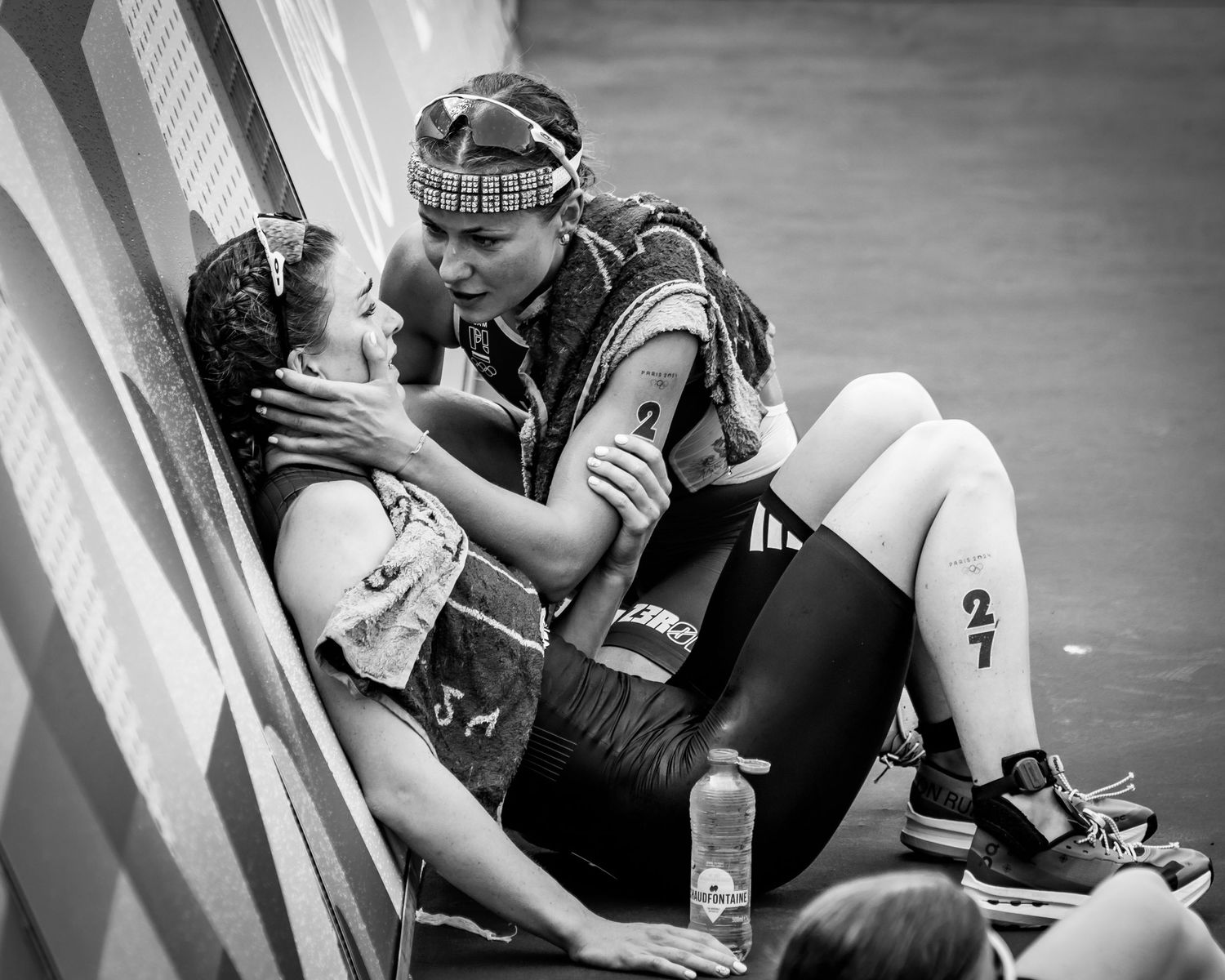 Two athletes share an intimate moment against a wall during a sports competition.