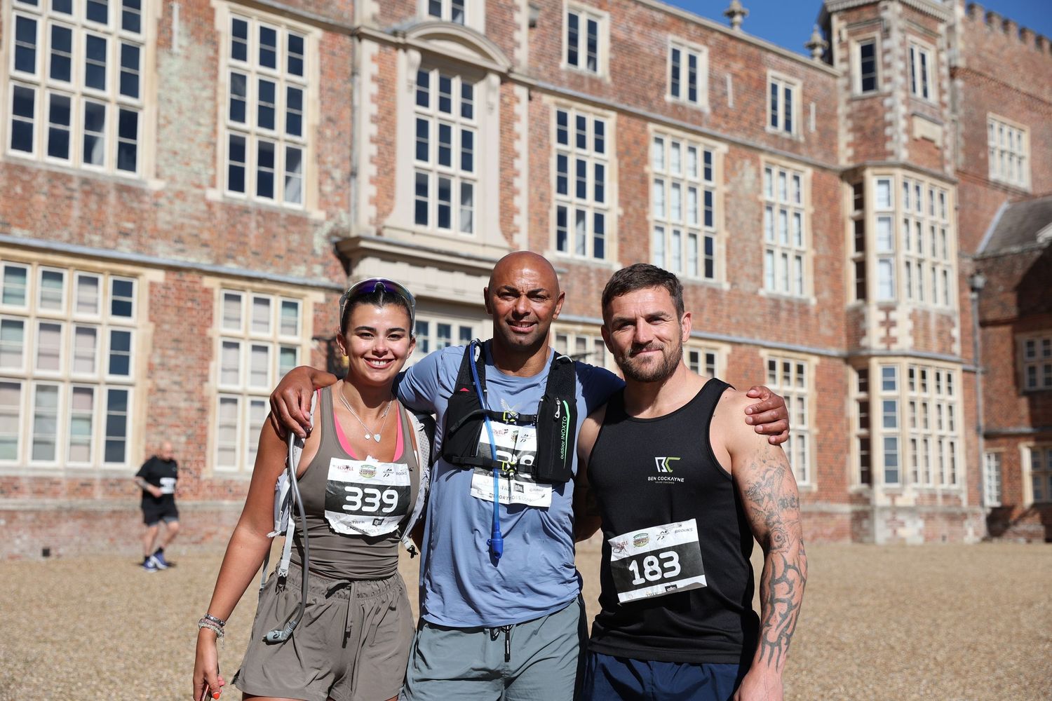 Three runners posing together after race in front of historic building.