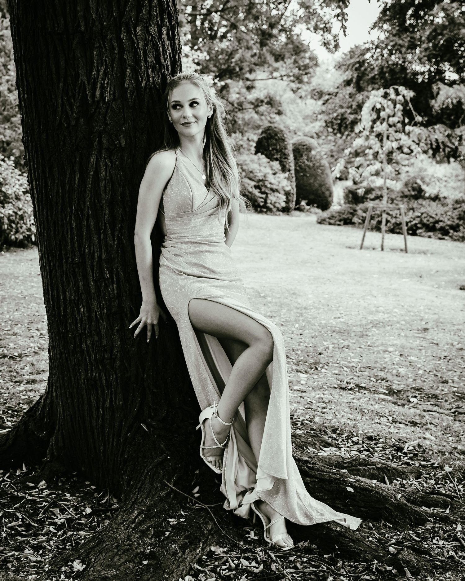 Black and white artistic portrait series showing a woman in a light dress posing elegantly against a tree trunk outdoors.