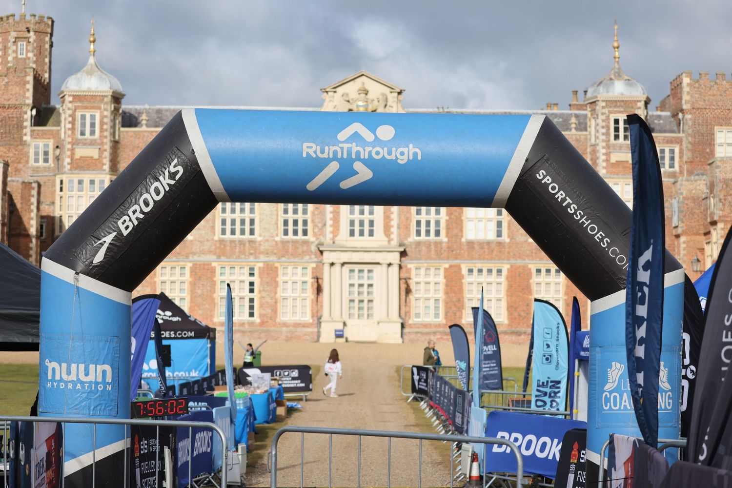 Event finish line with blue inflatable arch and banners in front of historic brick building.