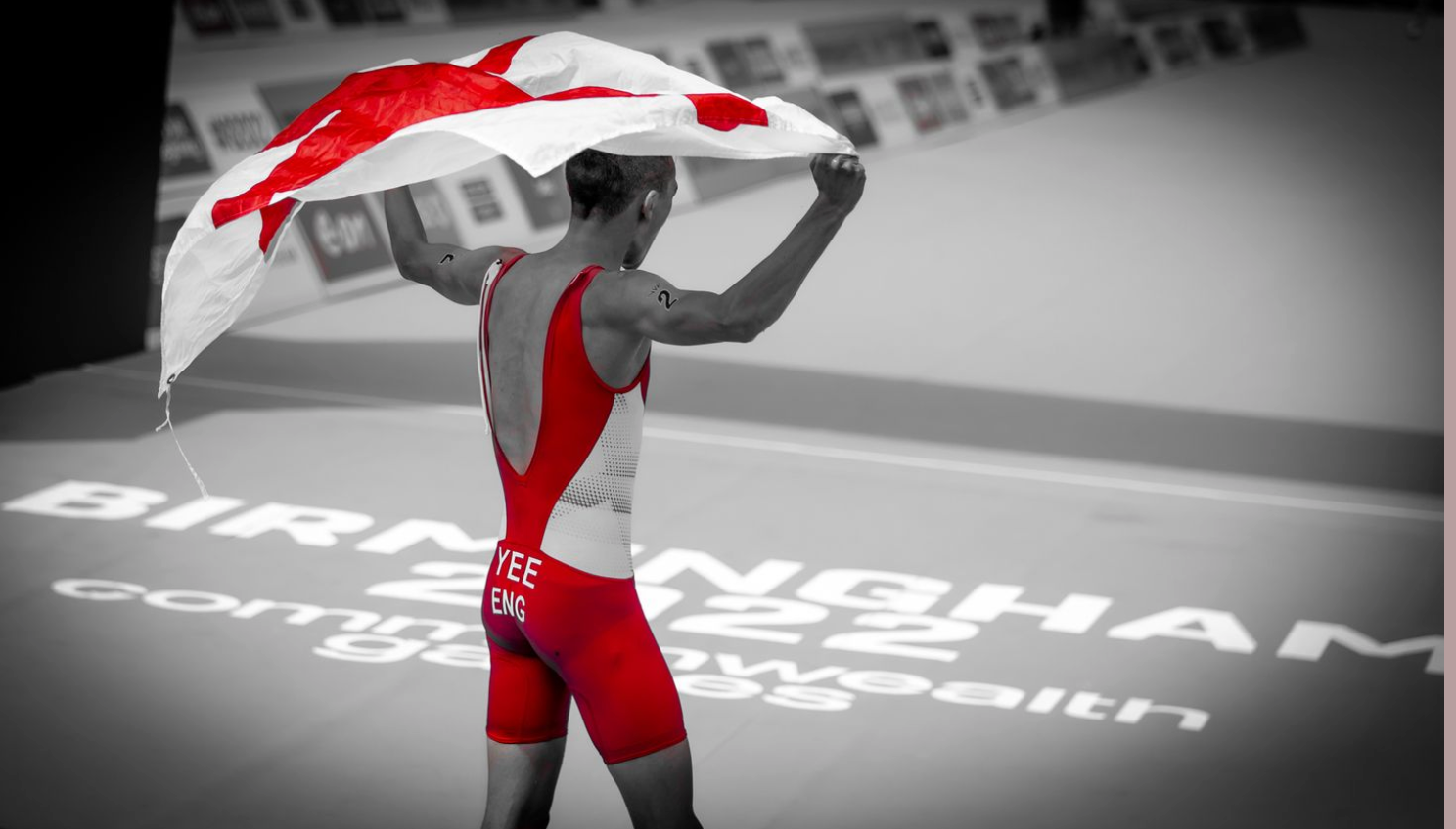 Athlete waves flag in celebration after victory at Birmingham championship event.