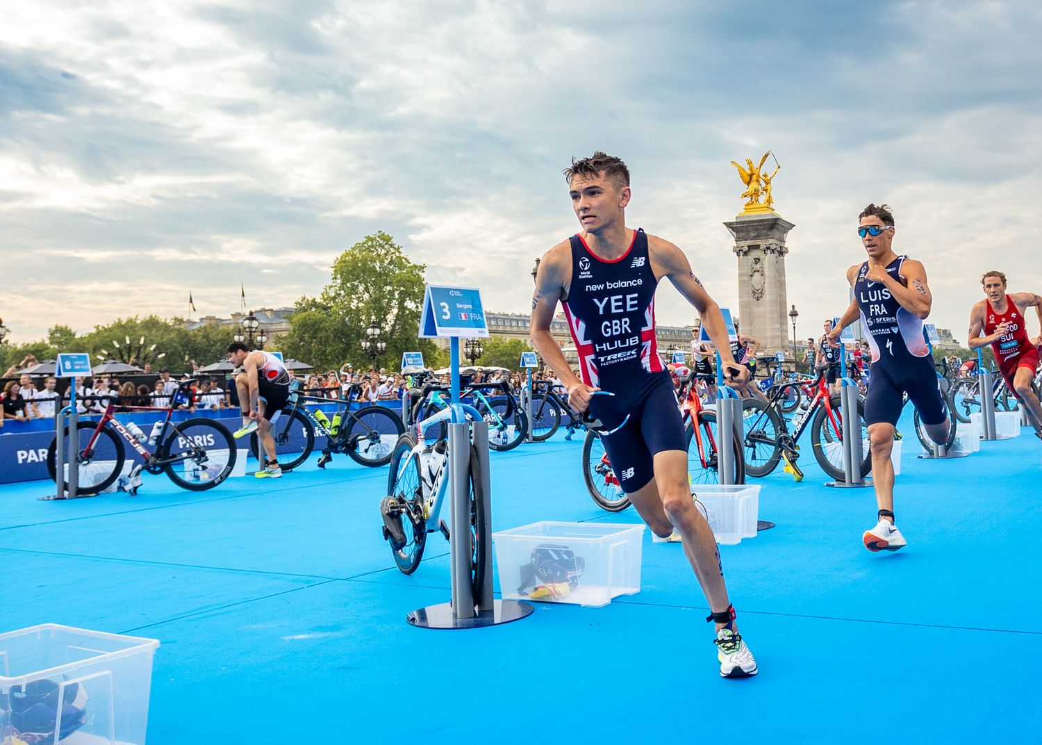 Athletes competing in triathlon race on blue running course.