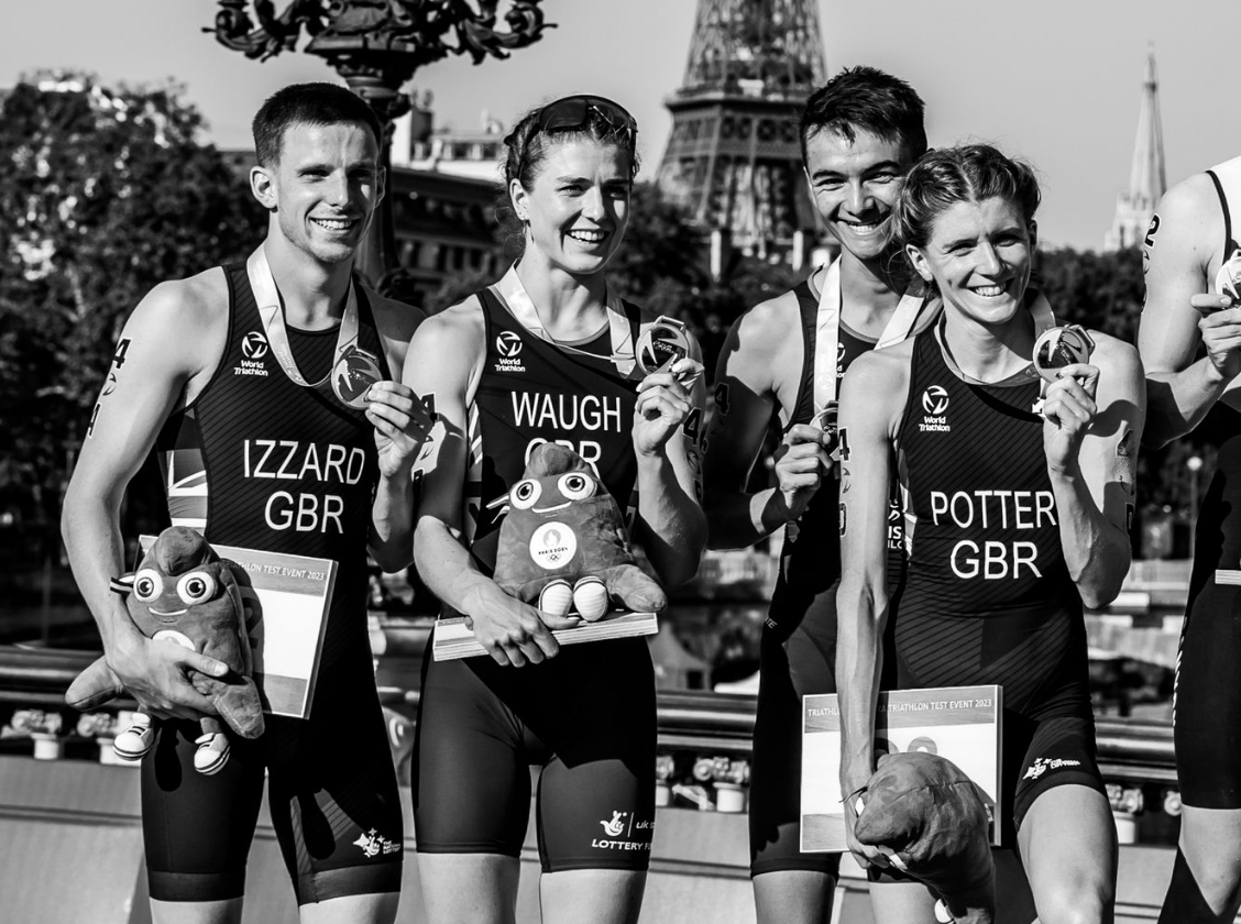 Athletes pose with trophies at a triathlon event with the Eiffel Tower in the background.