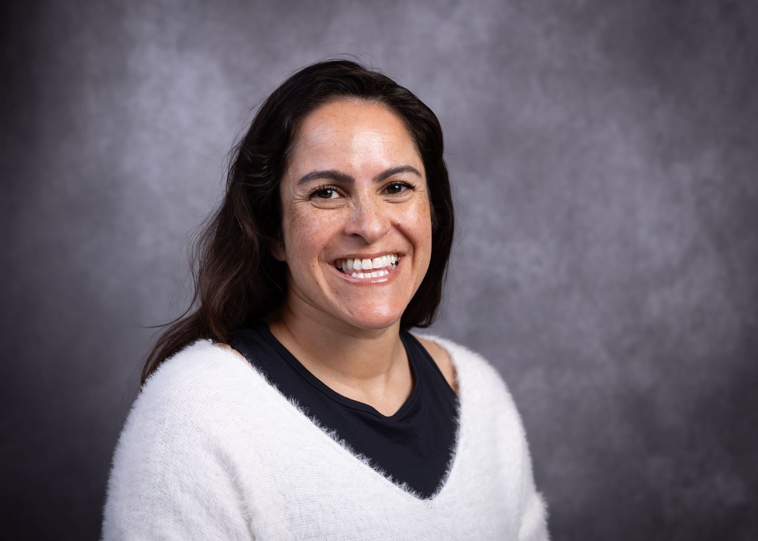 Professional headshot portraits of a woman in a white sweater against a dark gray background showing different expressions.