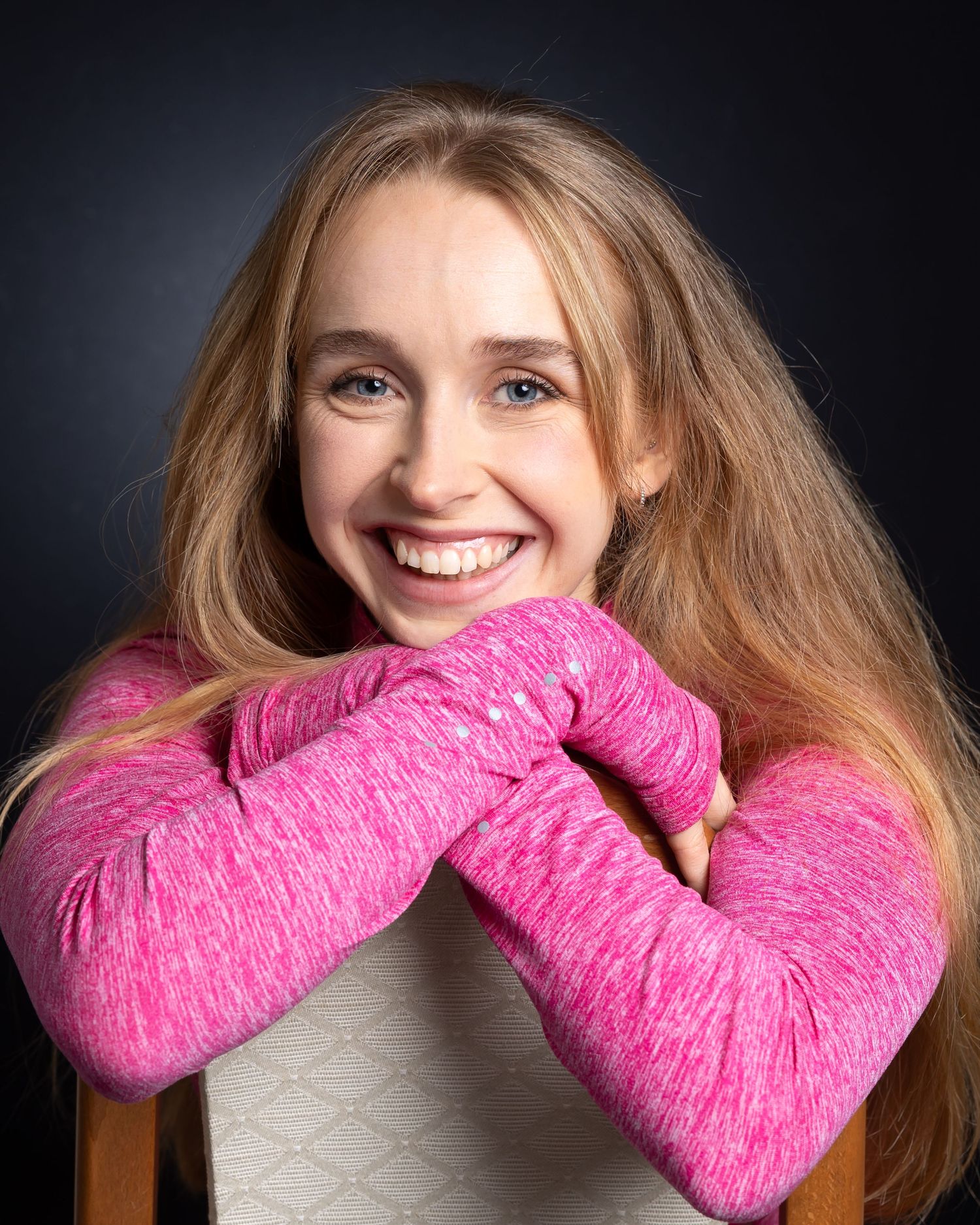 A series of photos showing someone wearing a bright pink fuzzy winter scarf against a dark background.