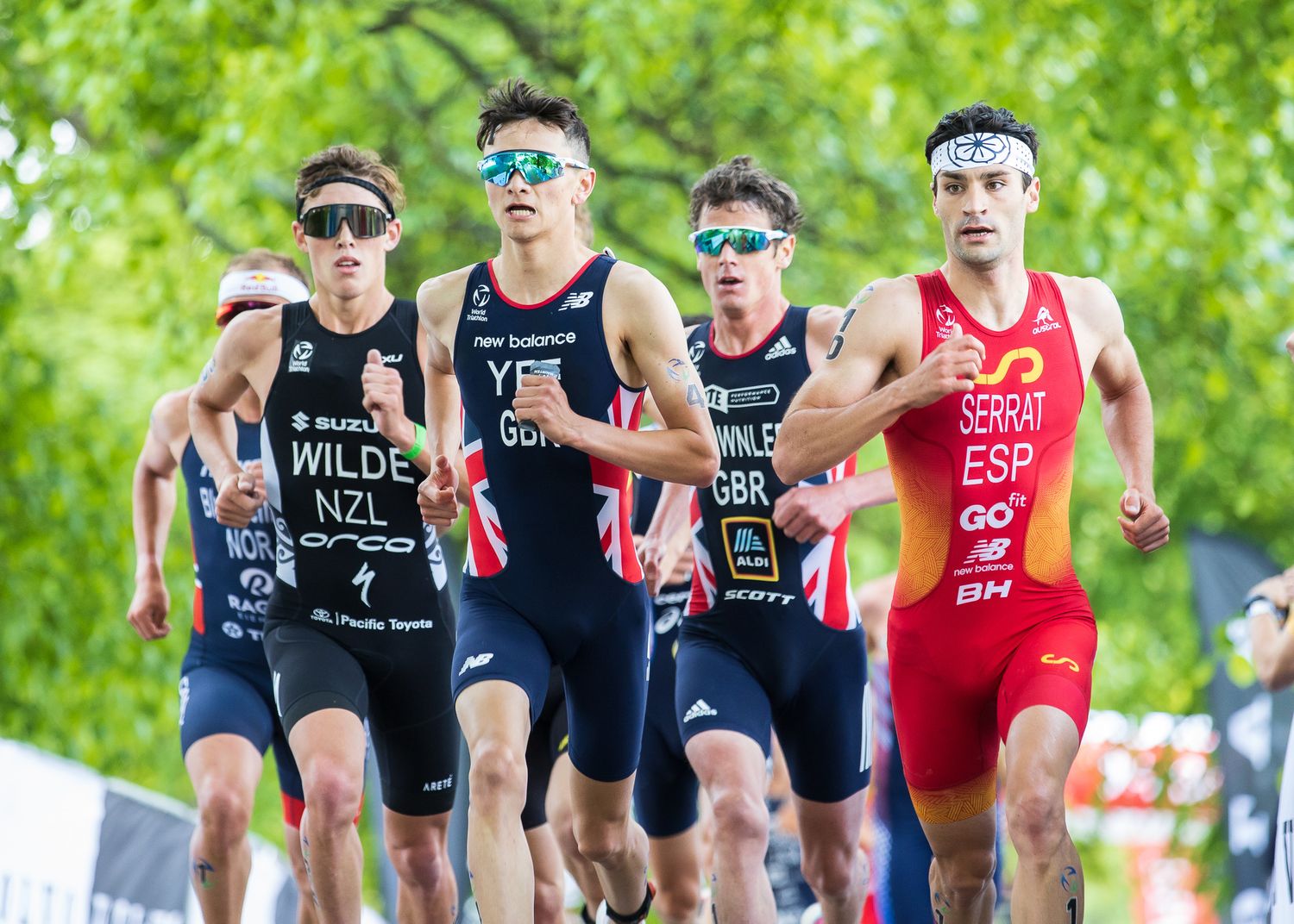 Professional triathletes competing in tight formation during a race with bright sunglasses and racing uniforms.