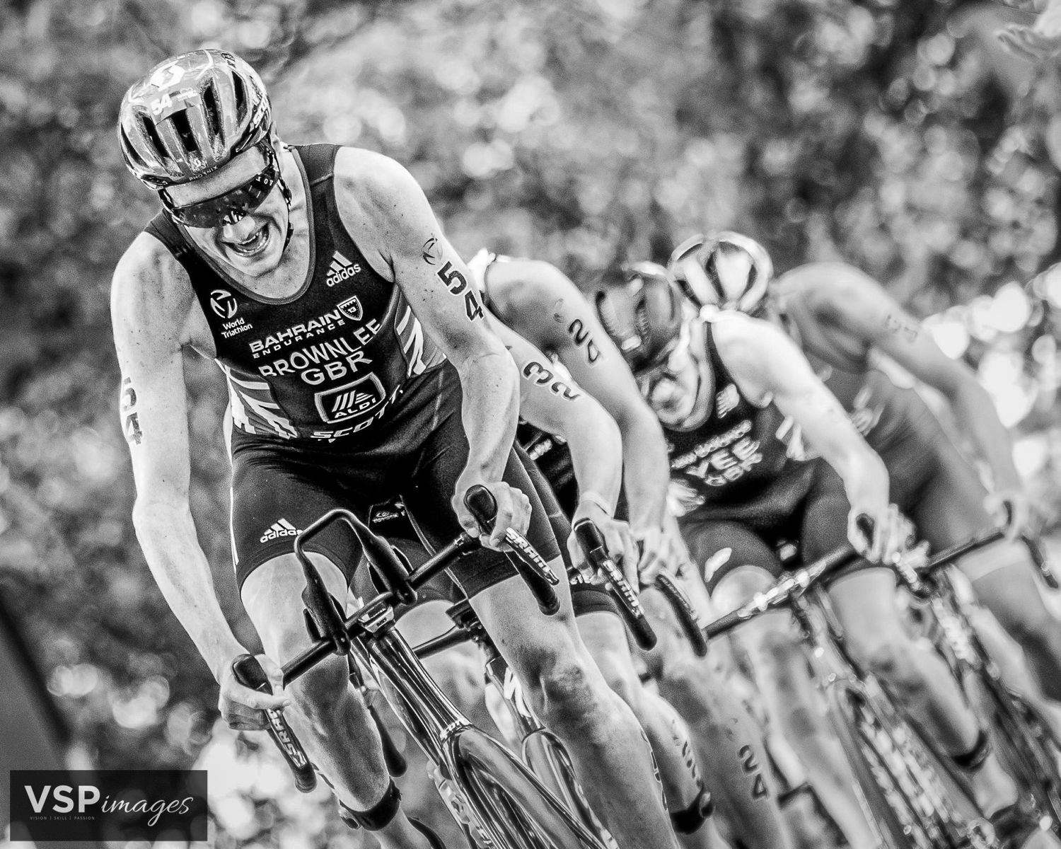 Black and white photo of ali brownlee racing in a competitive cycling event showing intense effort during the race.