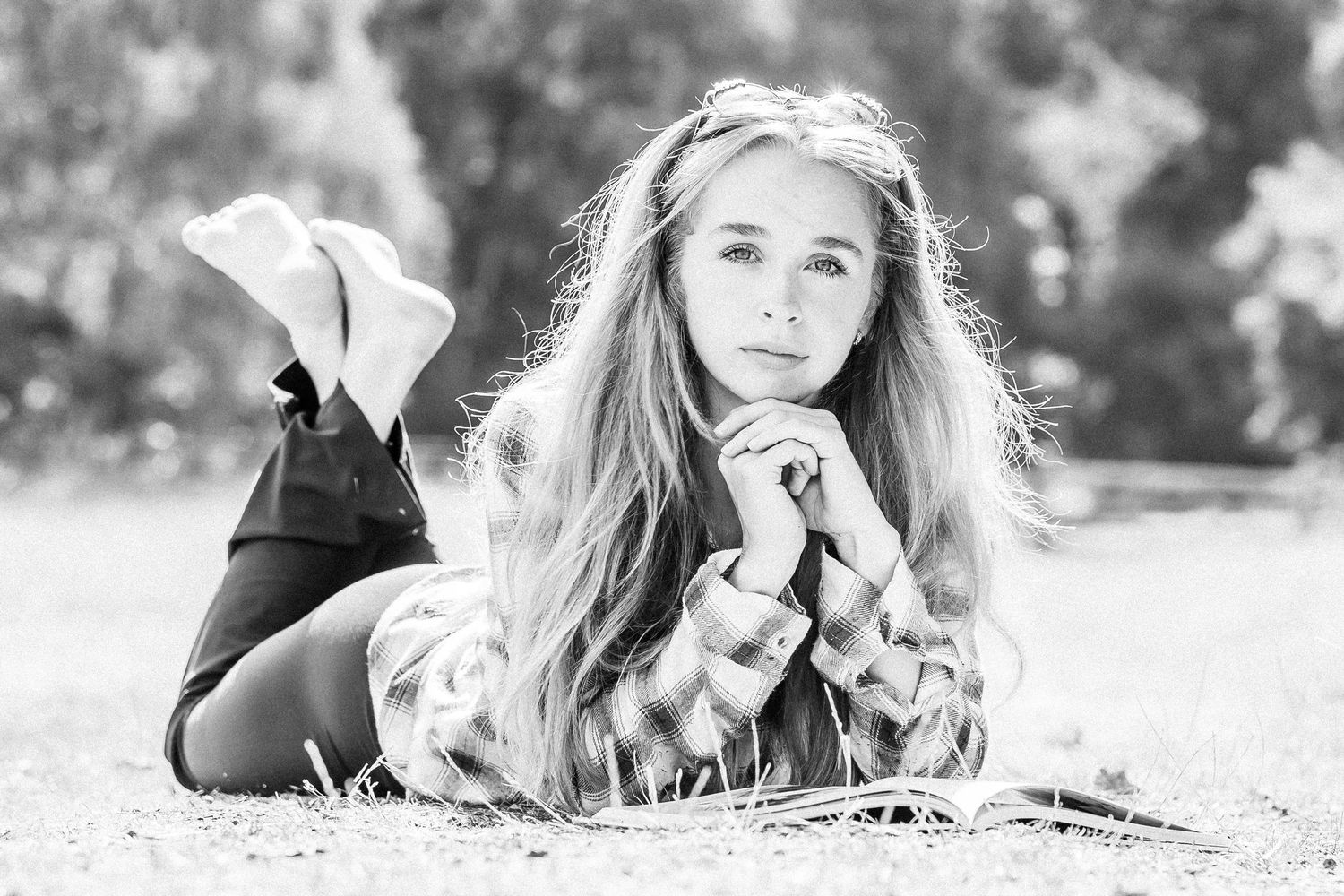 Black and white portrait of a young person lying on ground with long hair and casual pose.