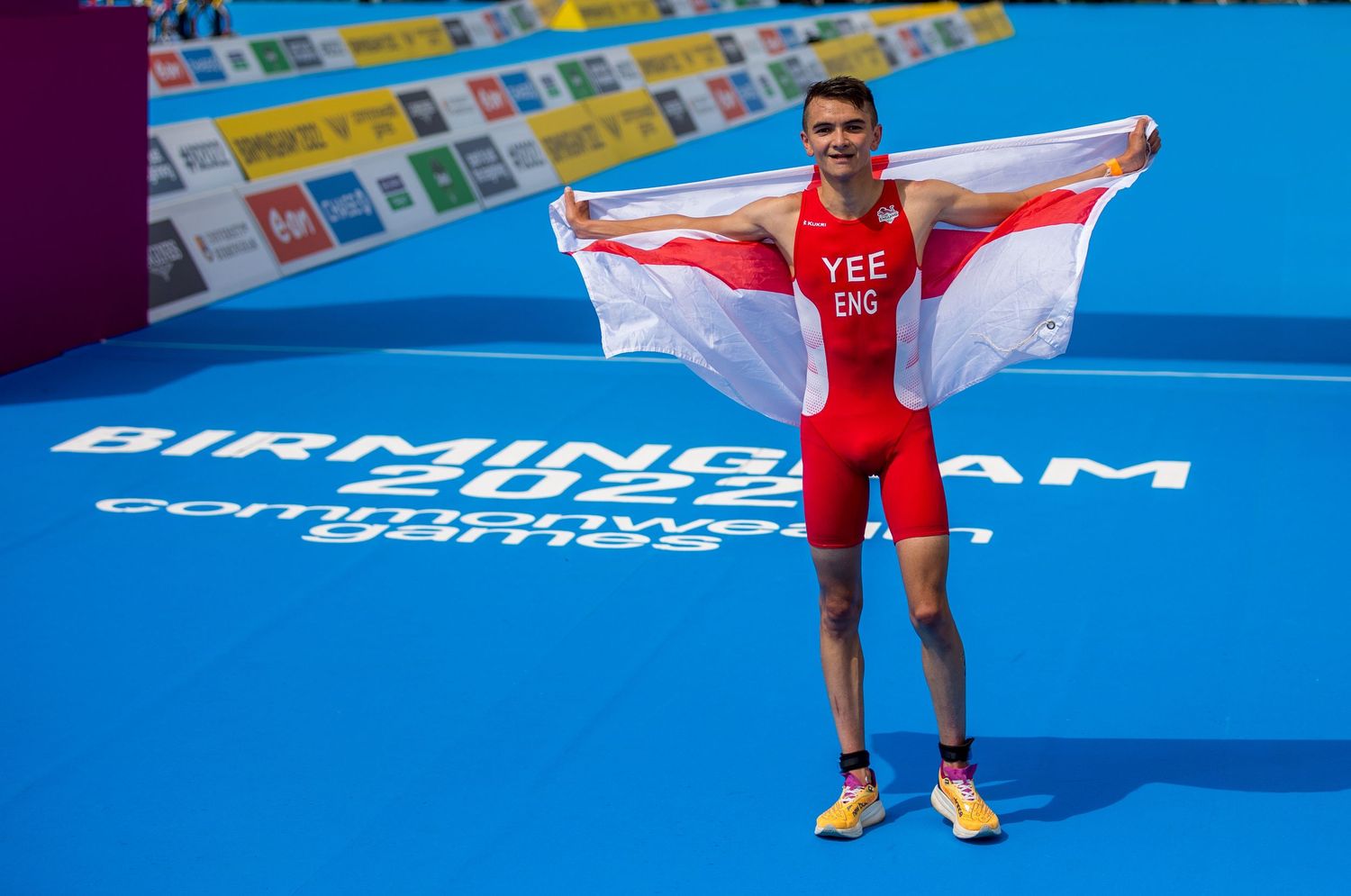 Alex yee celebrates on the podium holding the English flag at the Birmingham Commonwealth Games sports competition.