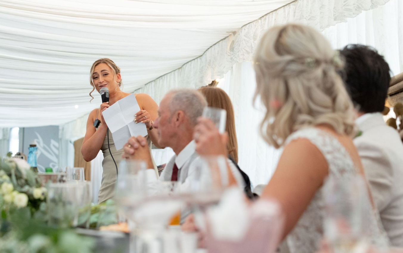 Wedding guests enjoying reception dinner under white fabric draped ceiling.