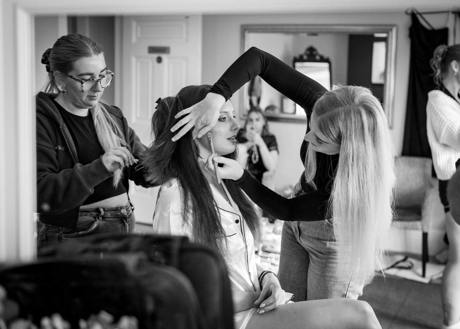 Student beauticians in white uniforms practice beauty treatments and hairstyling techniques during a cosmetology class.