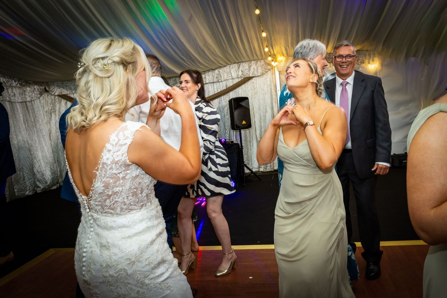 Two wedding guests singing karaoke together at a reception party.