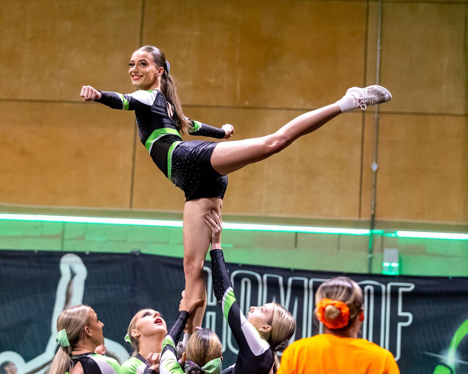Cheerleaders performing a stunt lift during a sports event.