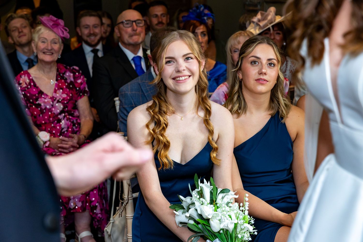 Wedding guests smile and celebrate during a reception while standing in a group at an indoor venue.