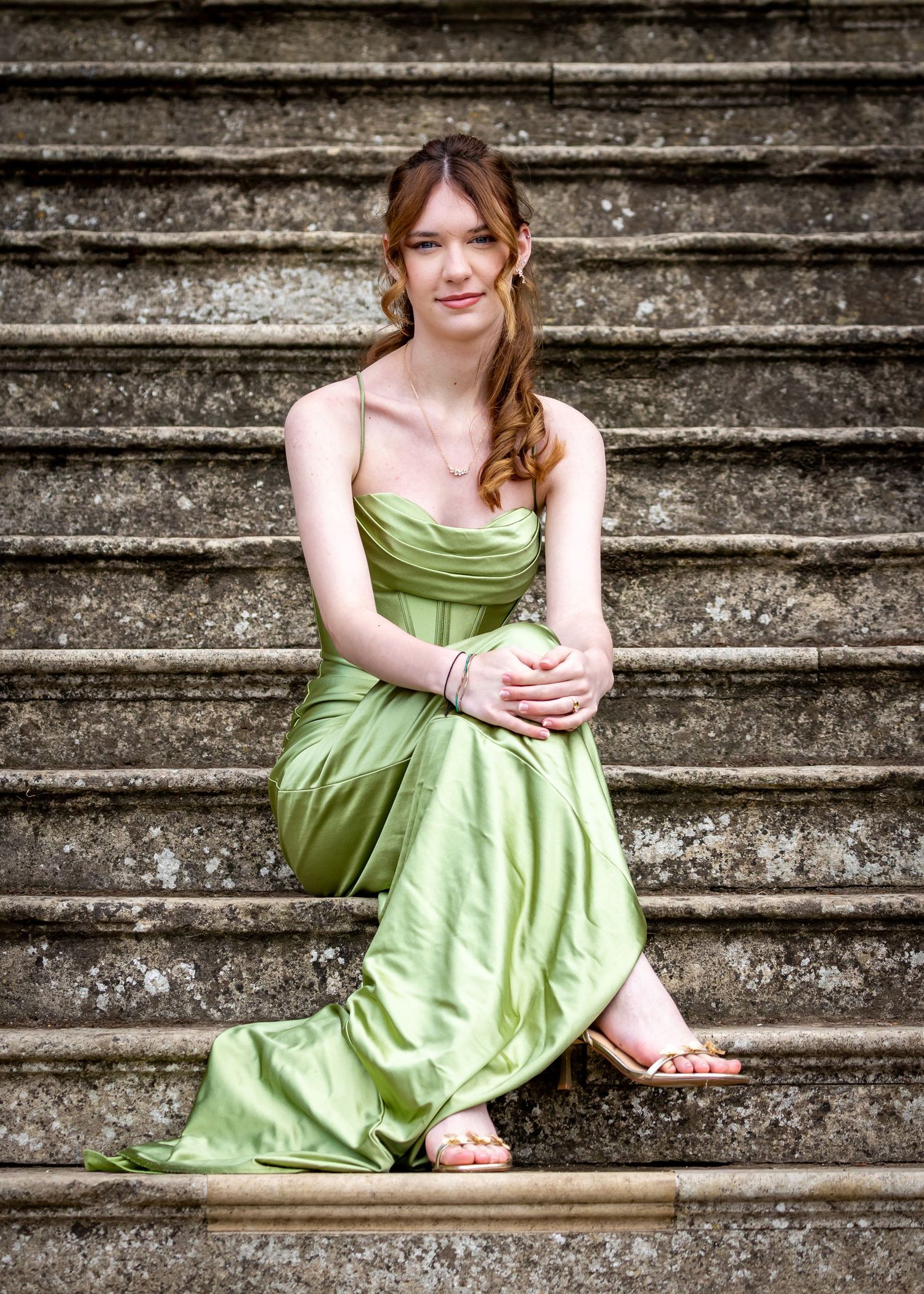 A series of six photos showing someone in a lime green formal dress sitting gracefully on concrete stairs in various poses.