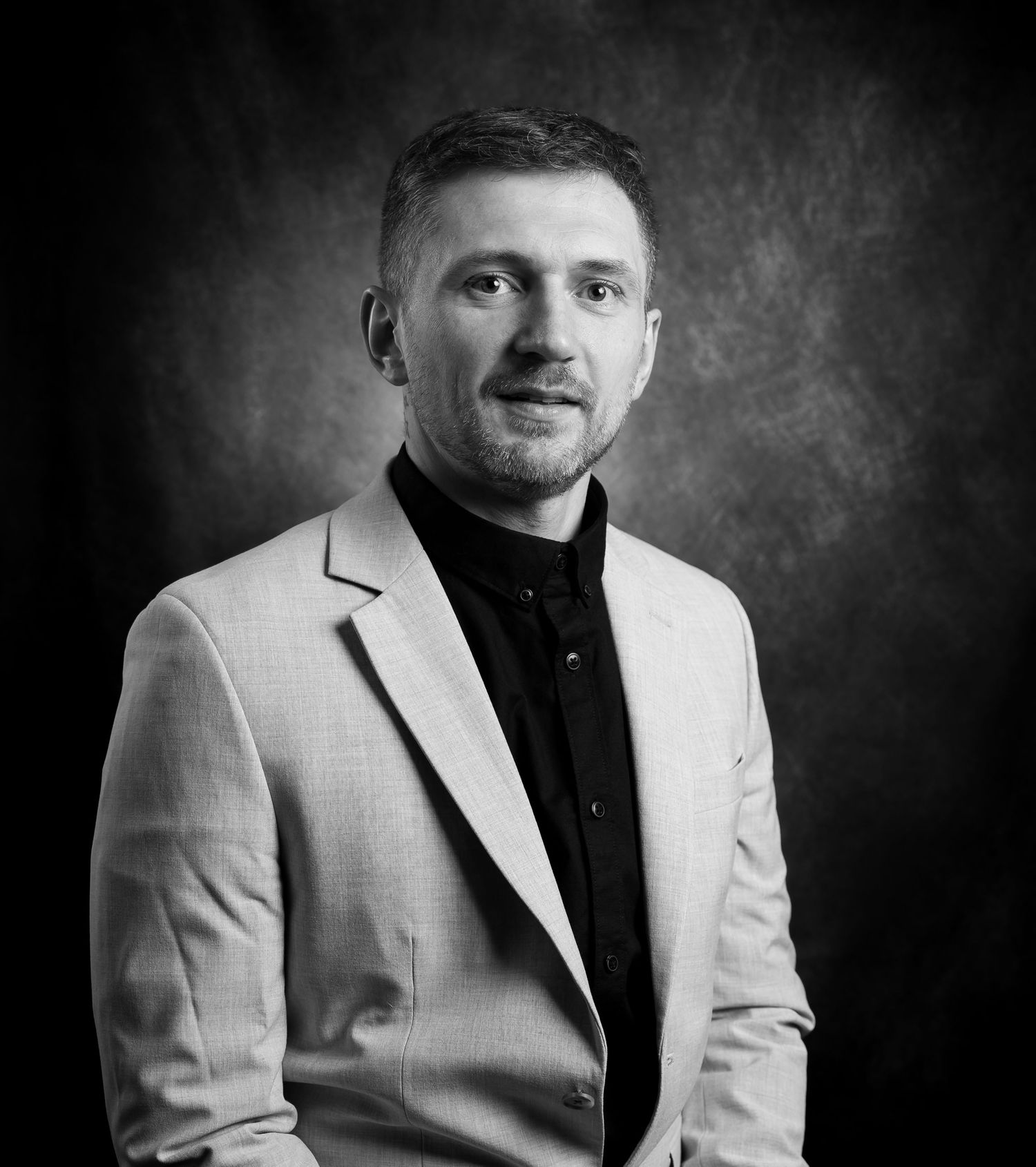 Professional black and white portrait series showing a person in a light blazer and dark shirt against a textured background.