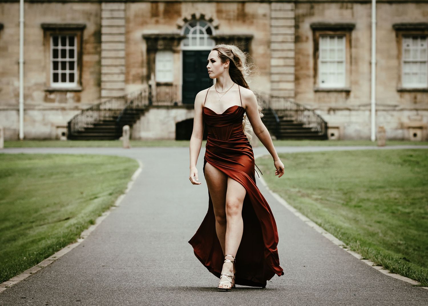 A series of images showing a flowing burgundy dress in motion against a backdrop of classic stone architecture.