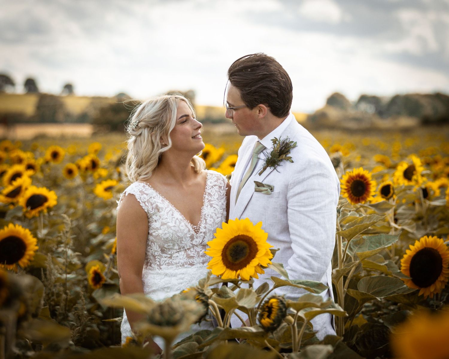 Romantic couple poses together in a golden sunflower field during sunset wedding photos.
