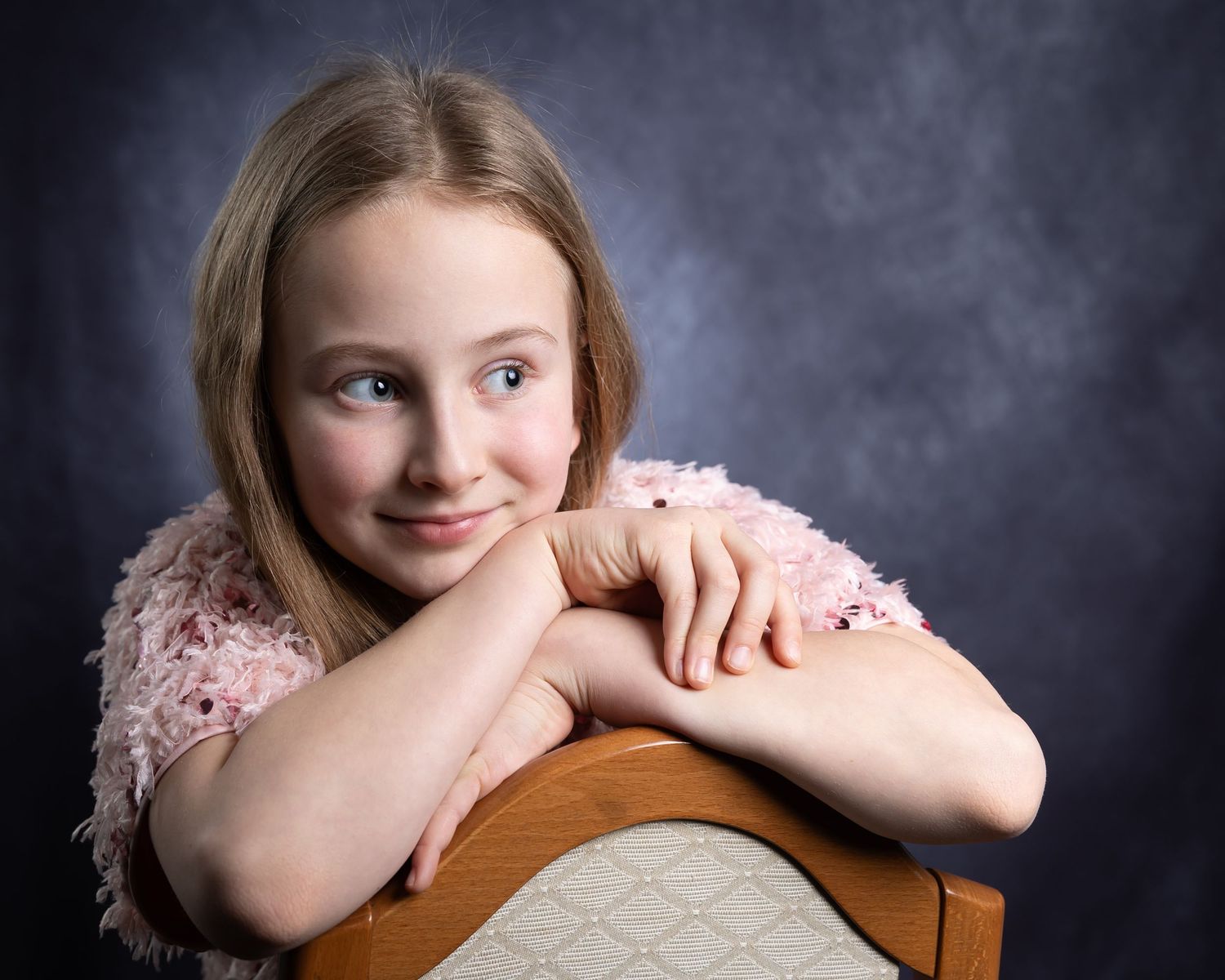 A series of four artistic studio portraits showing a child in a pink dress against a dark dramatic background.