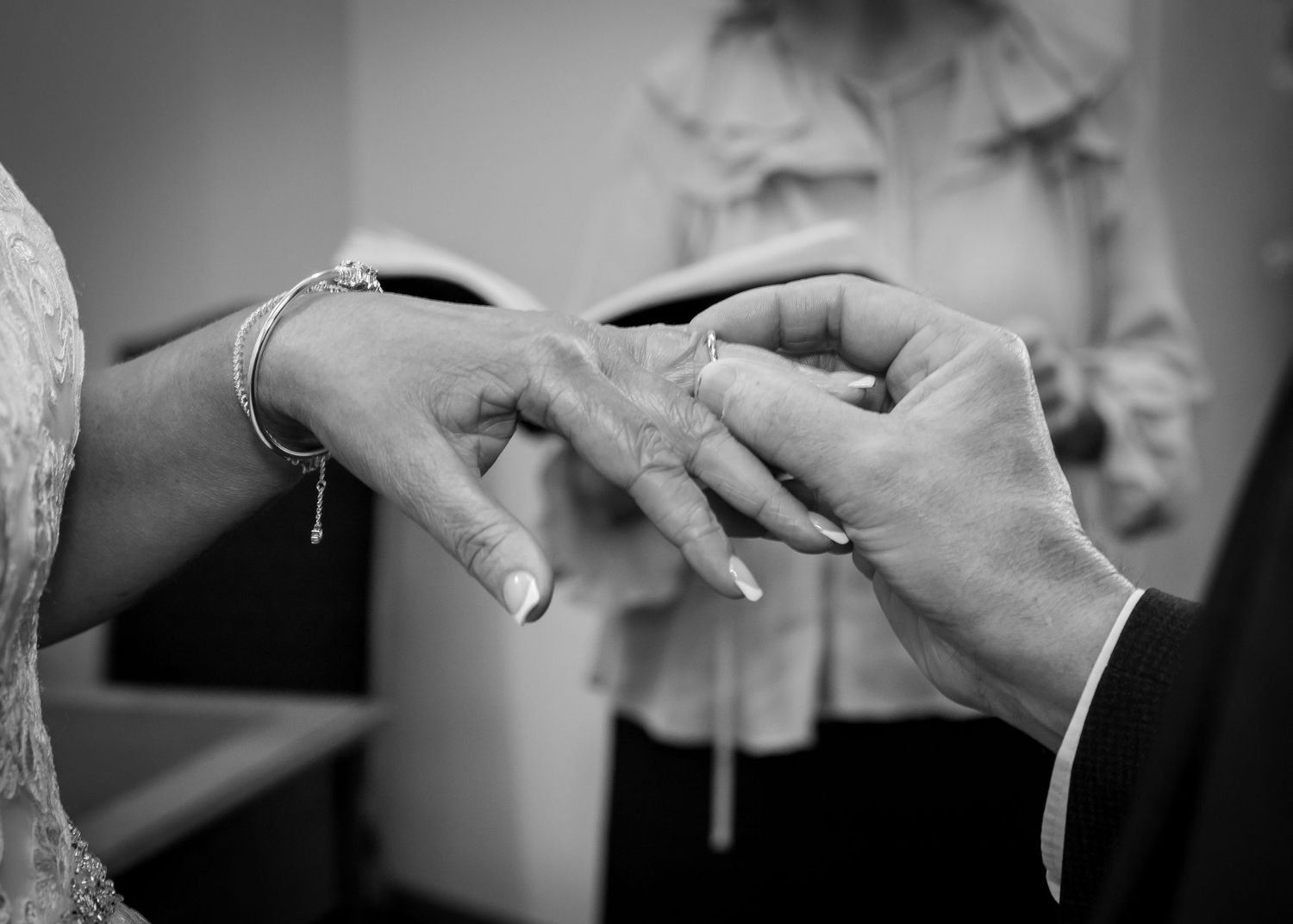 Black and white close-up photos showing exchange of wedding rings during a marriage ceremony.