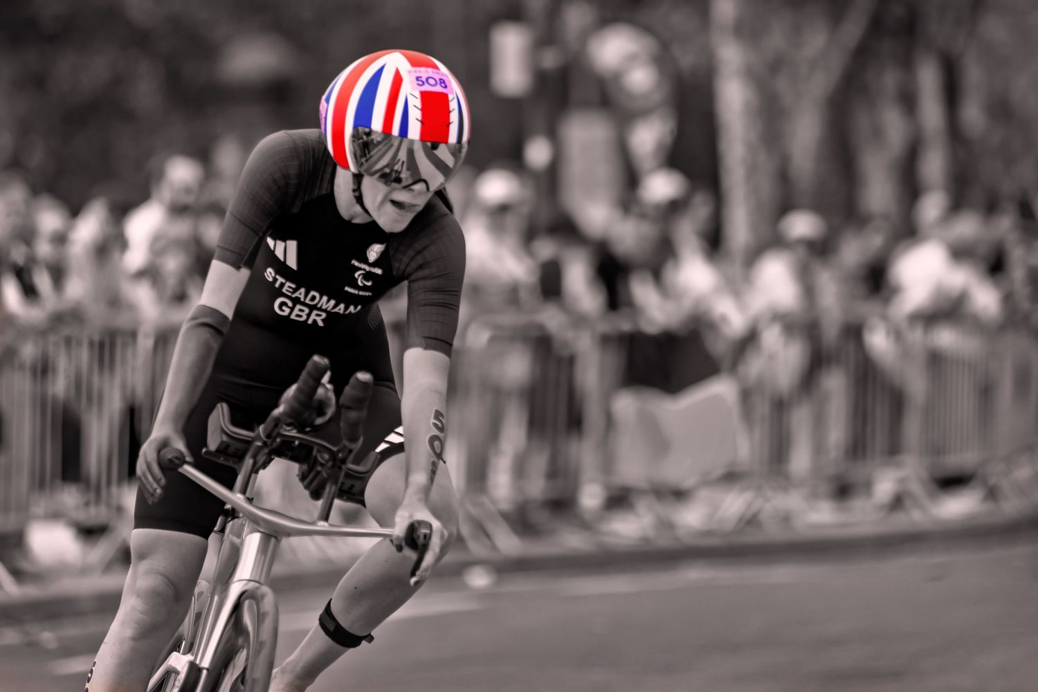 Cyclist in racing gear performs in a competitive triathlon event with spectators watching in the background. paris