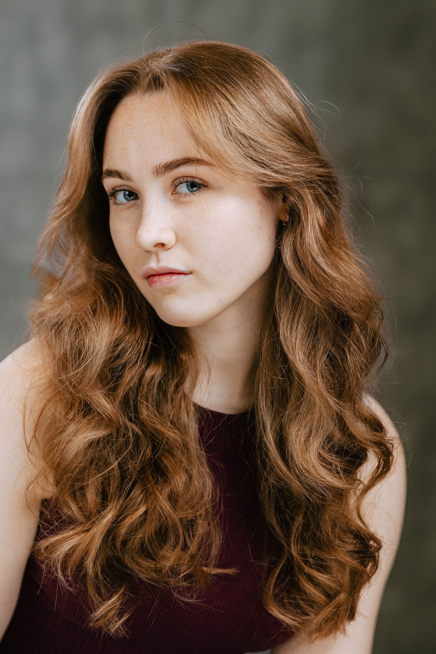 A series of portrait shots showing flowing auburn hair and a burgundy top against a dark background.