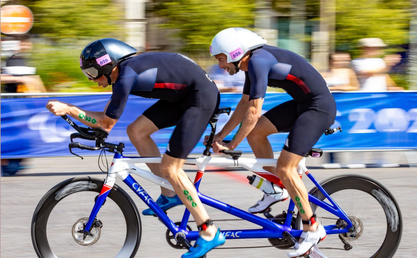 Motion blur of cyclists racing on road bikes during competitive event.
