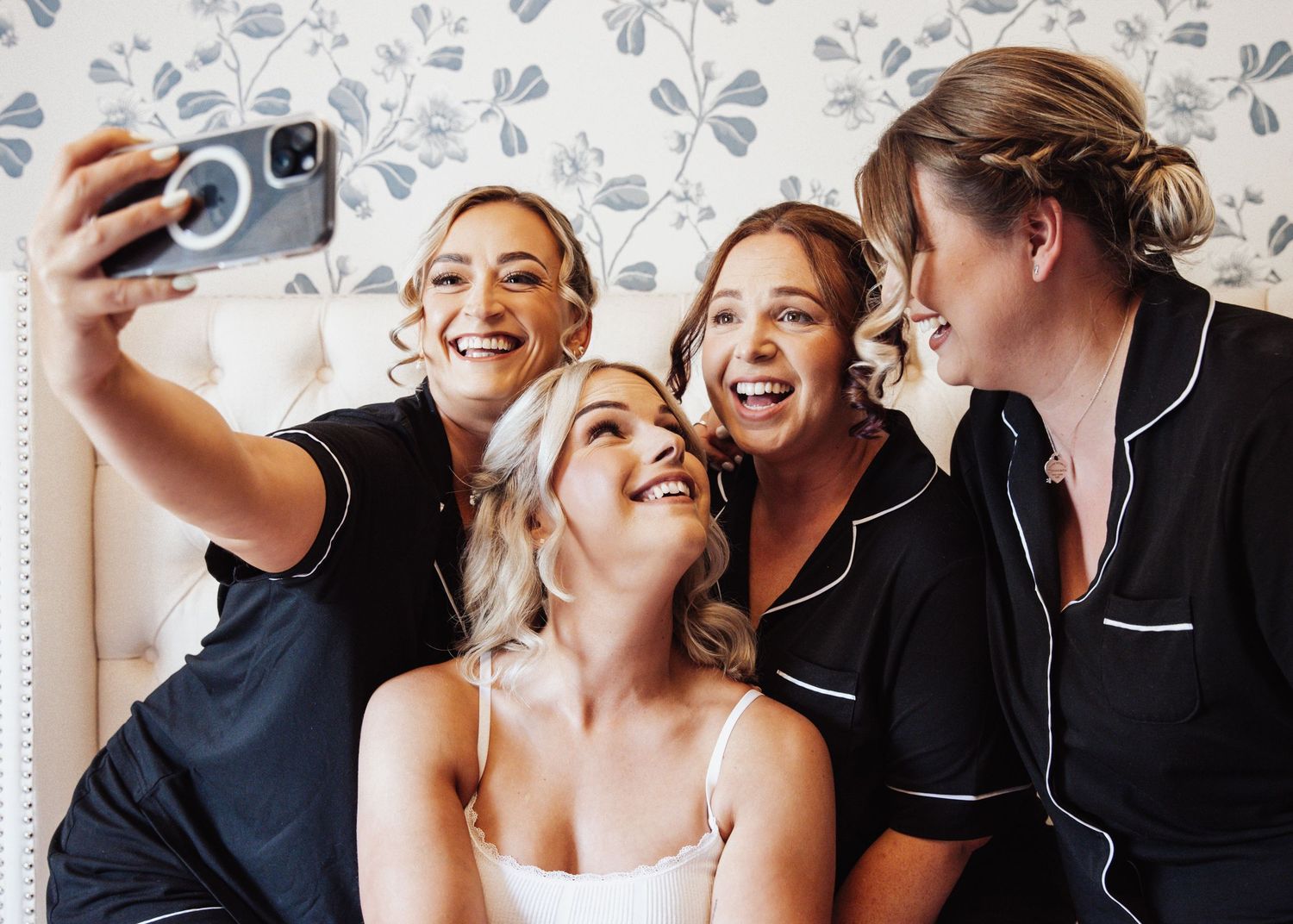 A group taking a celebratory selfie together during wedding preparations.